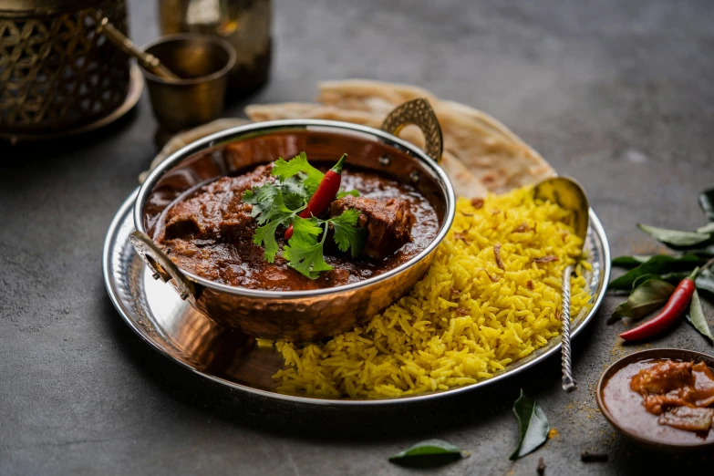 a meal on a plate has yellow rice and a serving spoon