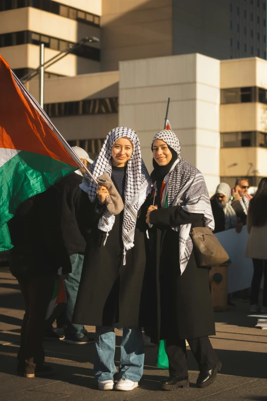 two women with their headscarves wrapped in paper and holding flags