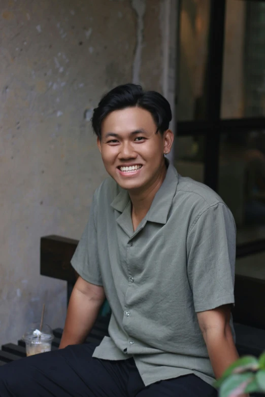 a smiling asian man sitting on a bench