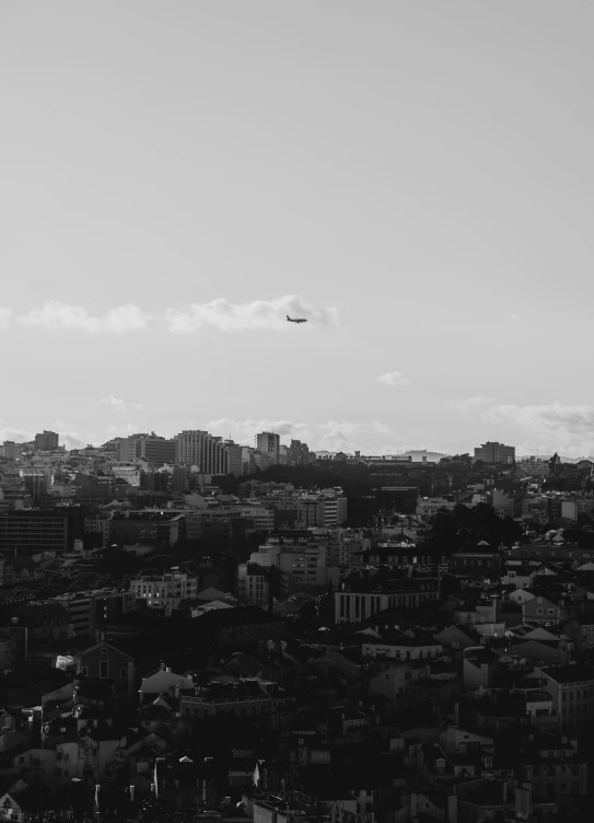 black and white po of city with an airplane in the sky