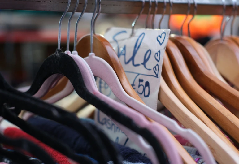 racks with clothes hanging on wooden rods and a price label