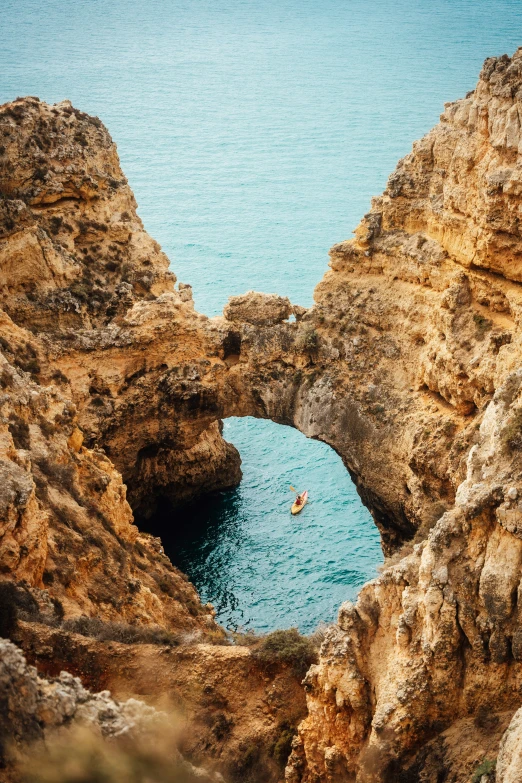 a person in a boat near a rock formation