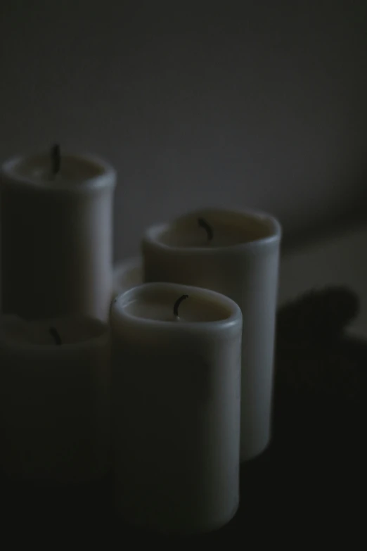 three white candles lit up in the dark