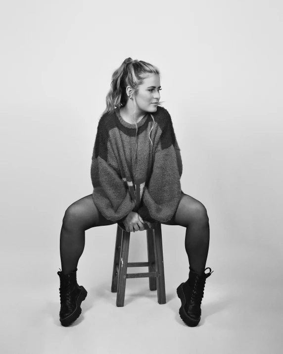 a woman sits on top of a stool wearing boots