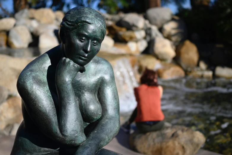 a woman sitting next to a statue of a  woman