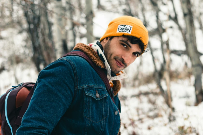 a man wearing a hat and backpack standing in the snow