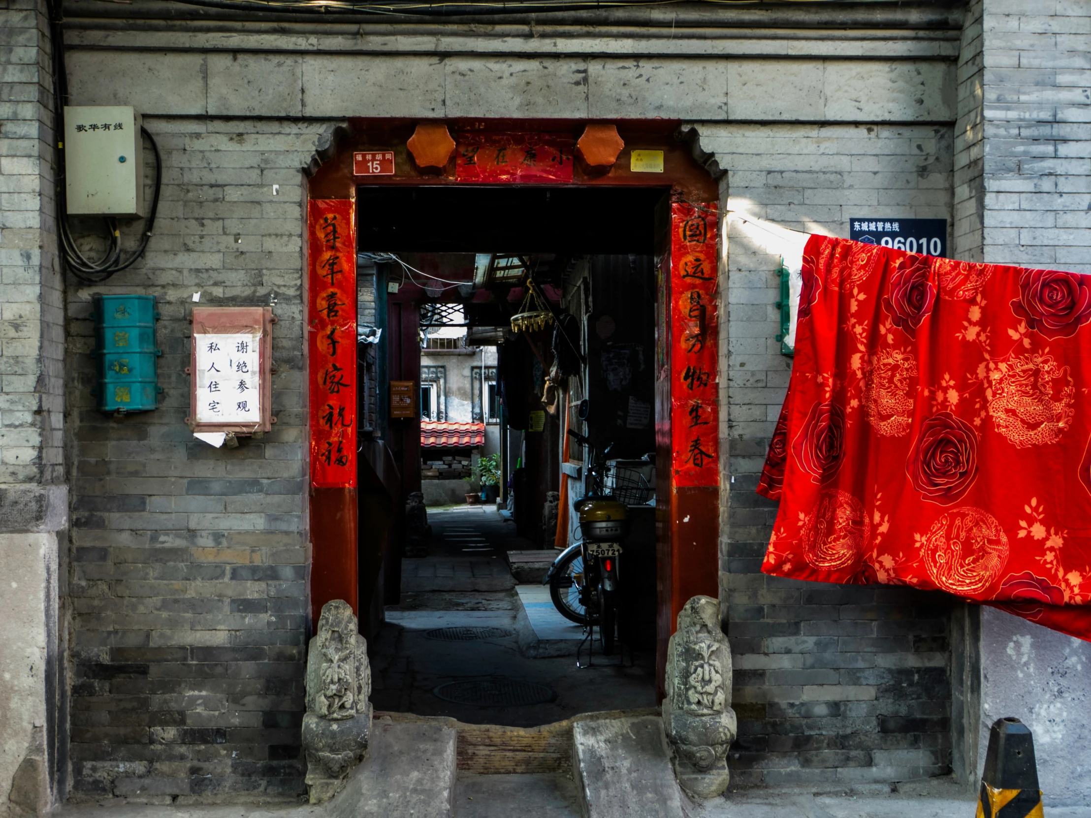 a red robe hanging on a clothes line next to an old door