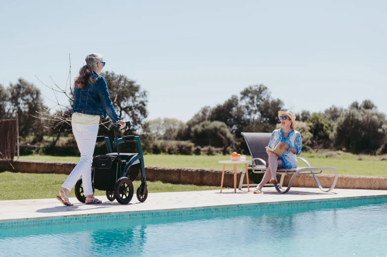 a woman is walking by the pool with a baby in a stroller