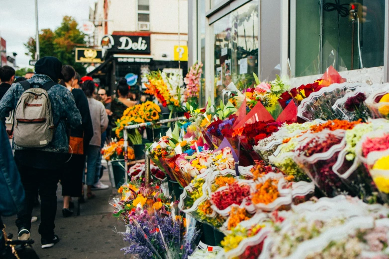 people walking by the flower shop with flowers