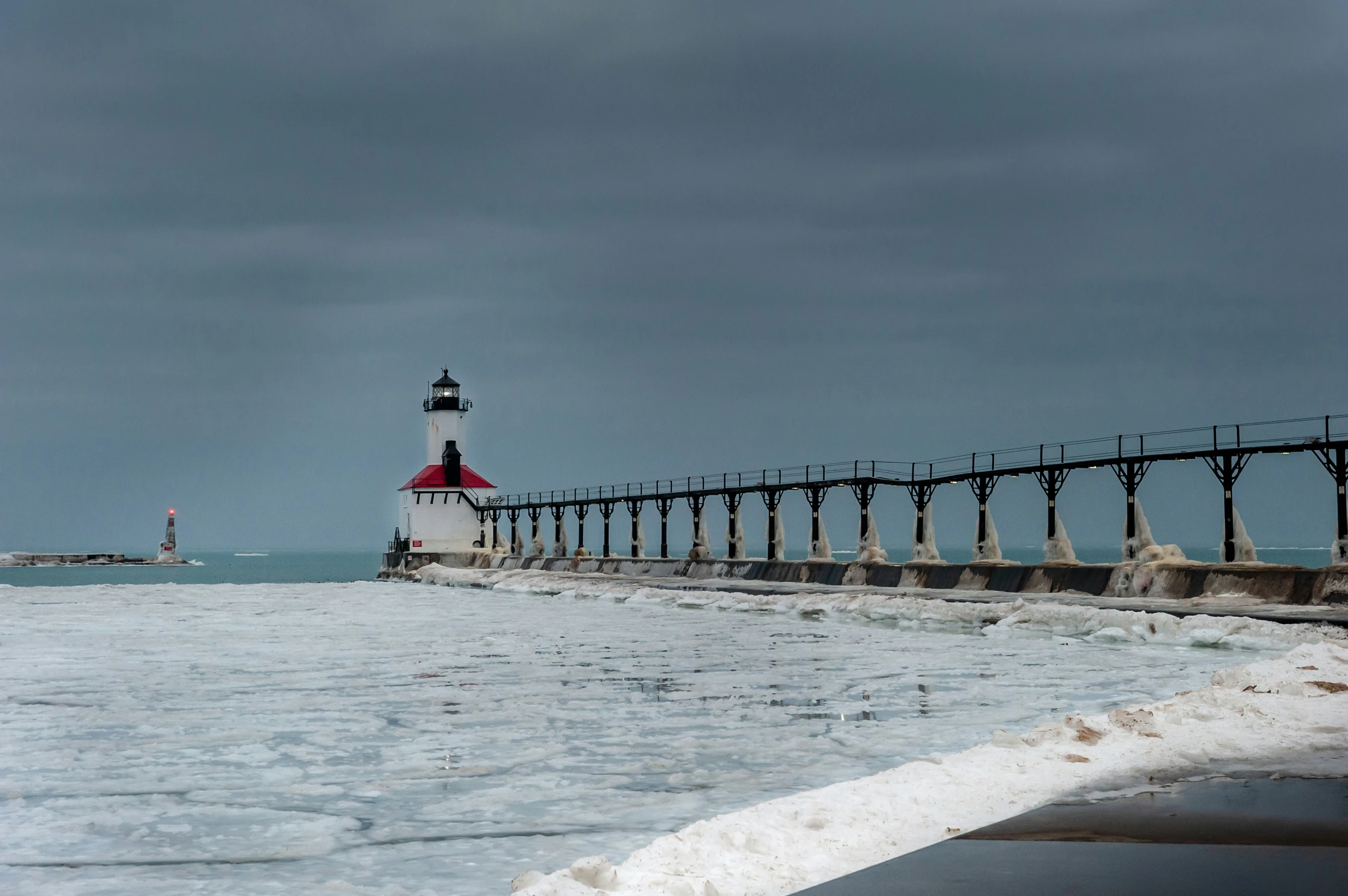 a lighthouse in the distance next to a beach with waves