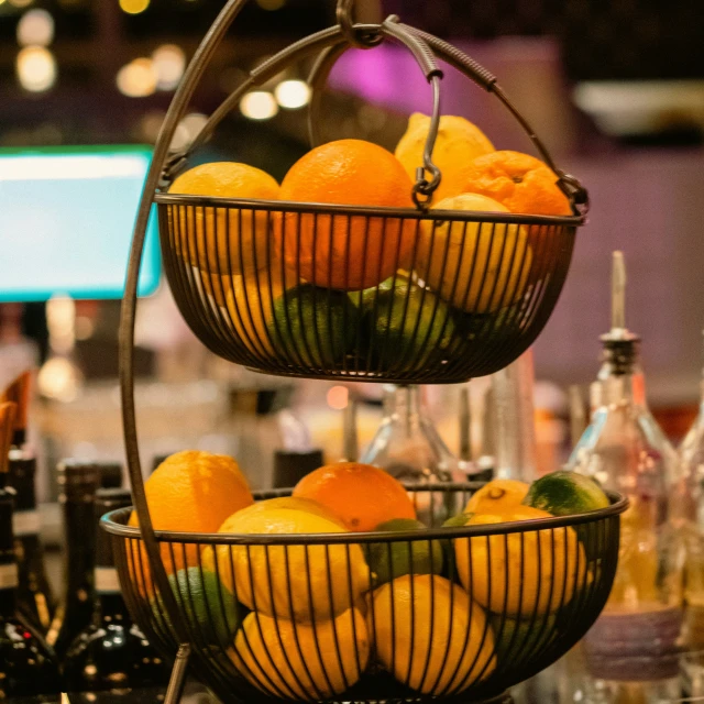 two metal baskets on top of each other filled with oranges and lemons