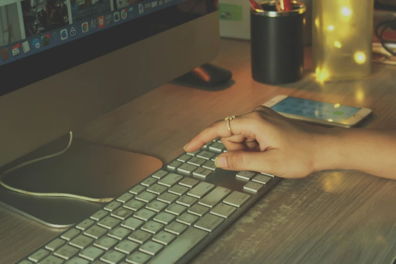 the person is using their computer keyboard on a desk