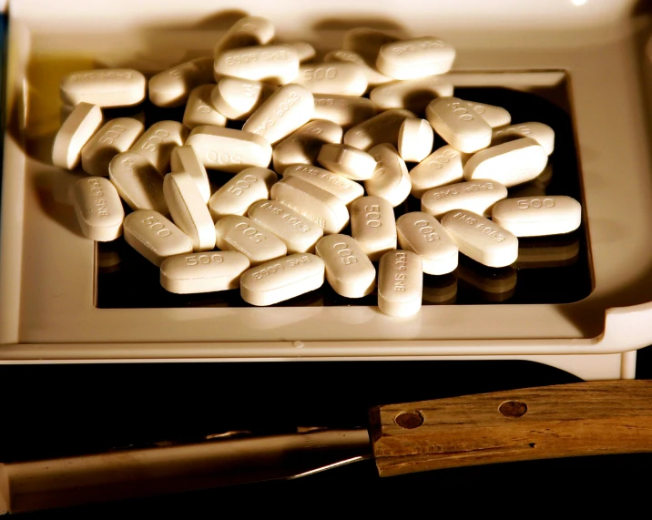 a bowl full of pill shaped tablets and a knife