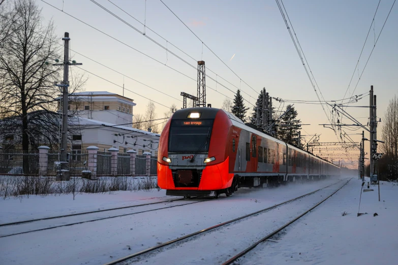 the red train is traveling on the tracks near power lines