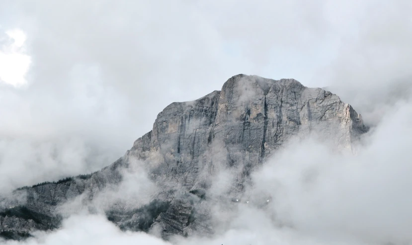 some mountain peaks covered in clouds as they sit