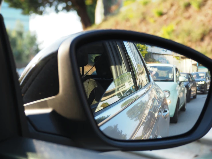 a side mirror reflection of cars on the street