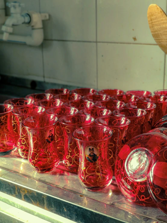 a table with many red glass cups lined up and sitting on top of each other