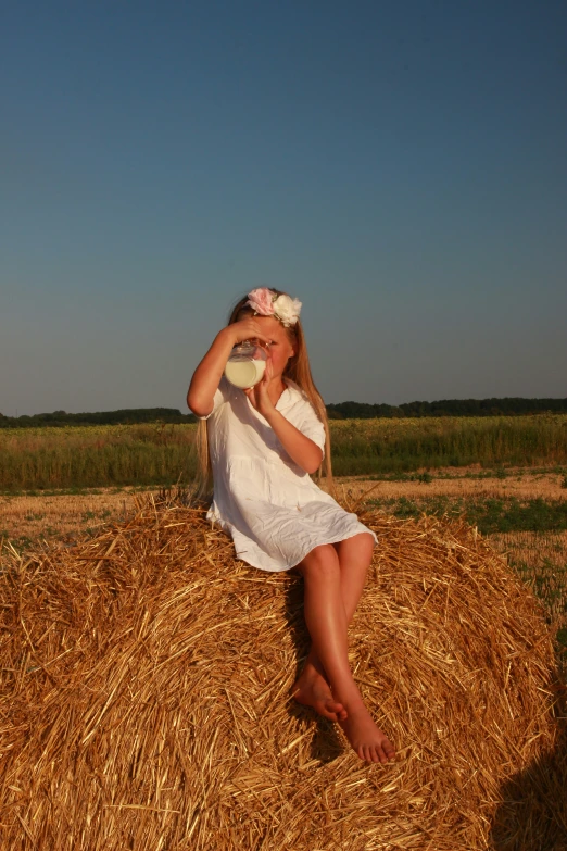 a woman is sitting on a pile of hay holding her frisbee