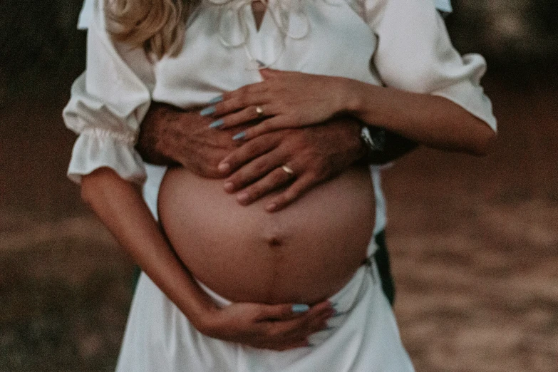 the pregnant woman is looking at her hand on her stomach