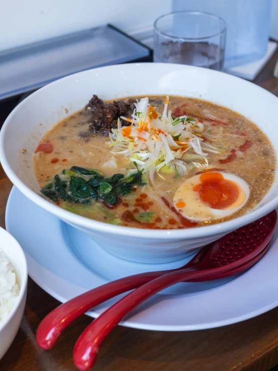 a bowl of soup and chopsticks on a plate