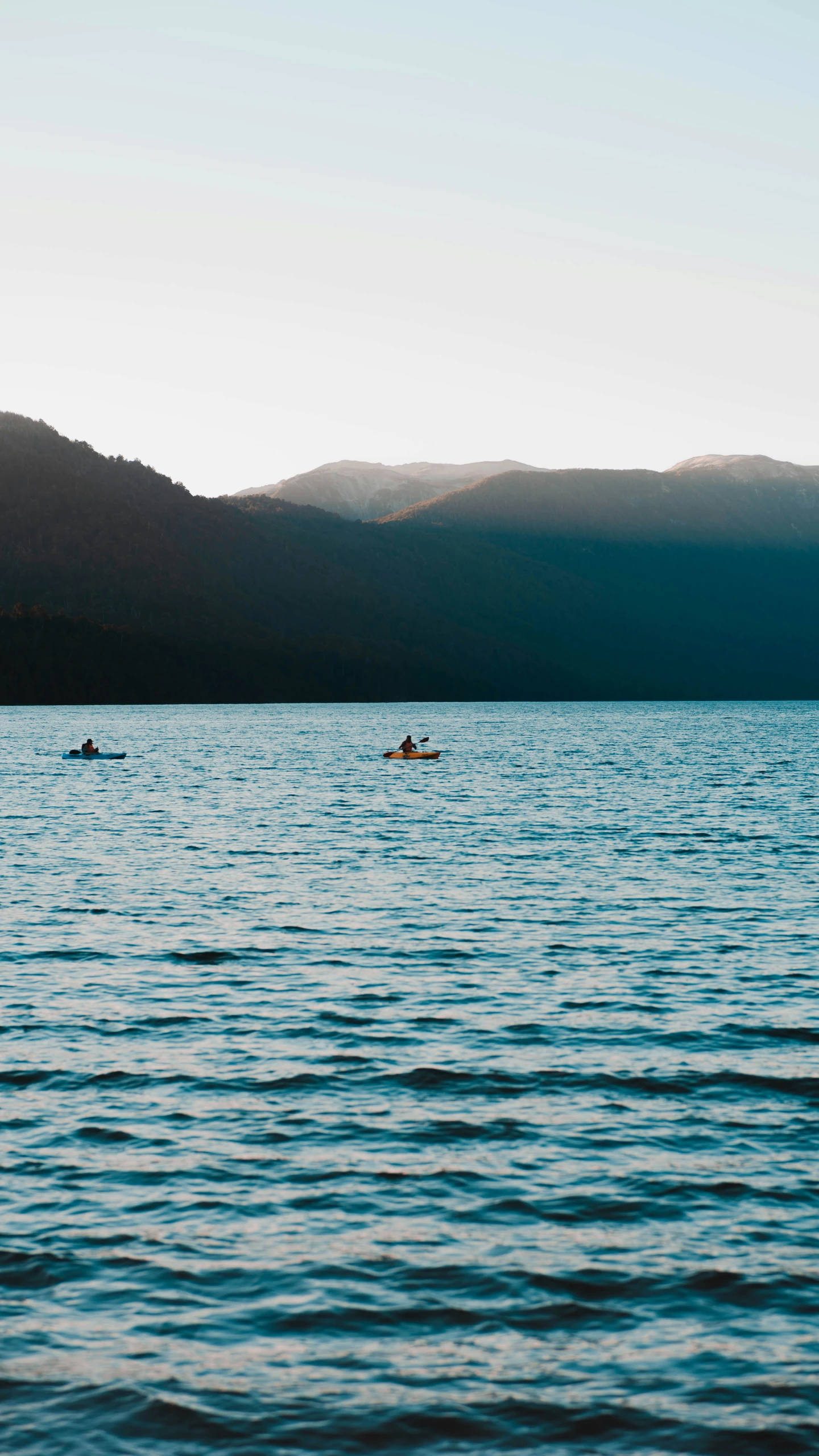 some people are paddling in small boats on the water