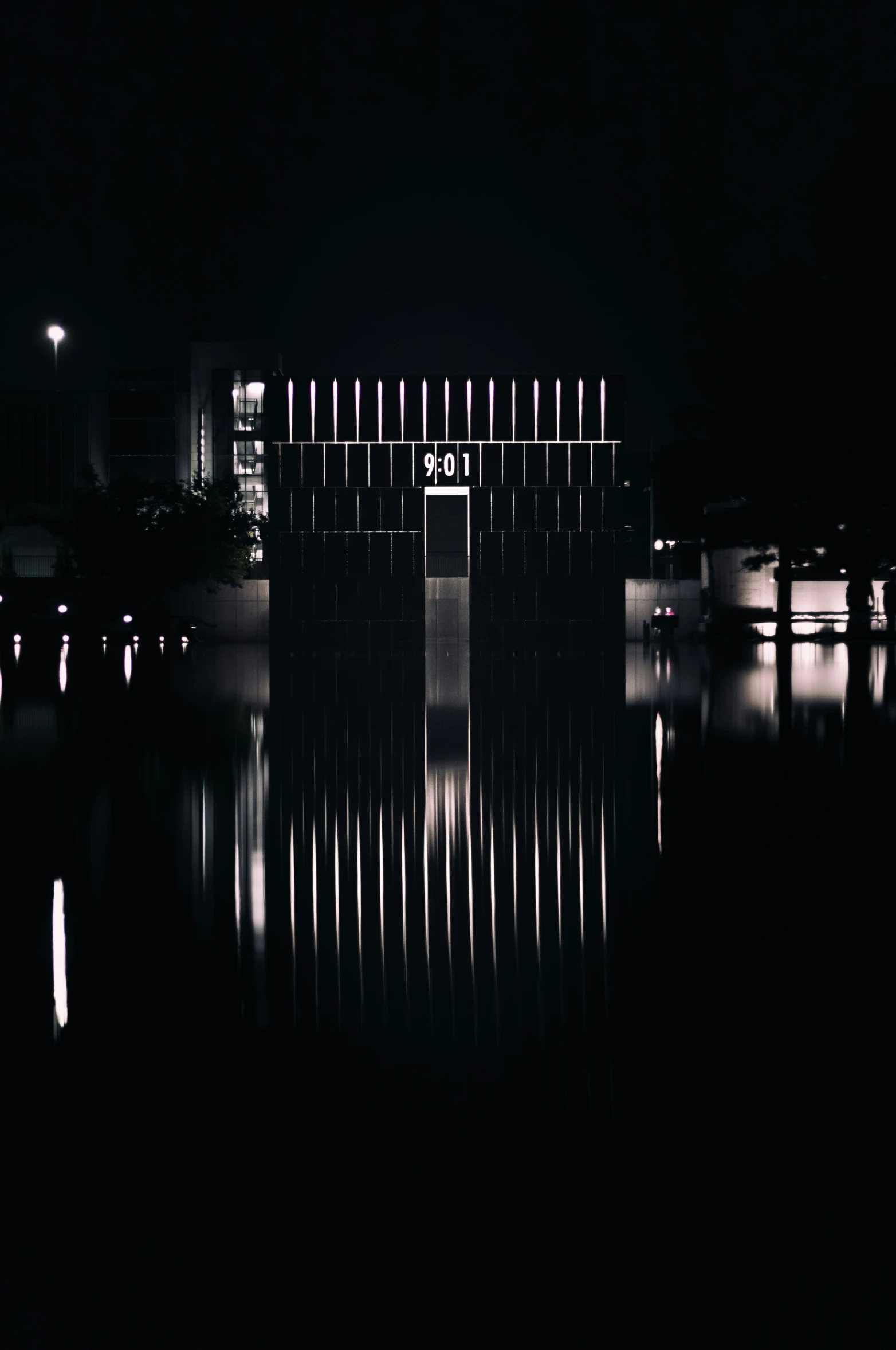 the front entrance to an illuminated building across water