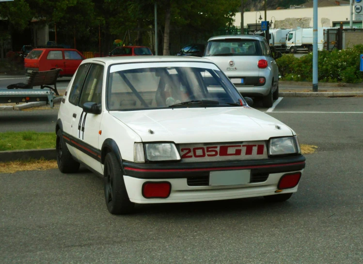 a white car sits on the side of the road in front of several vehicles