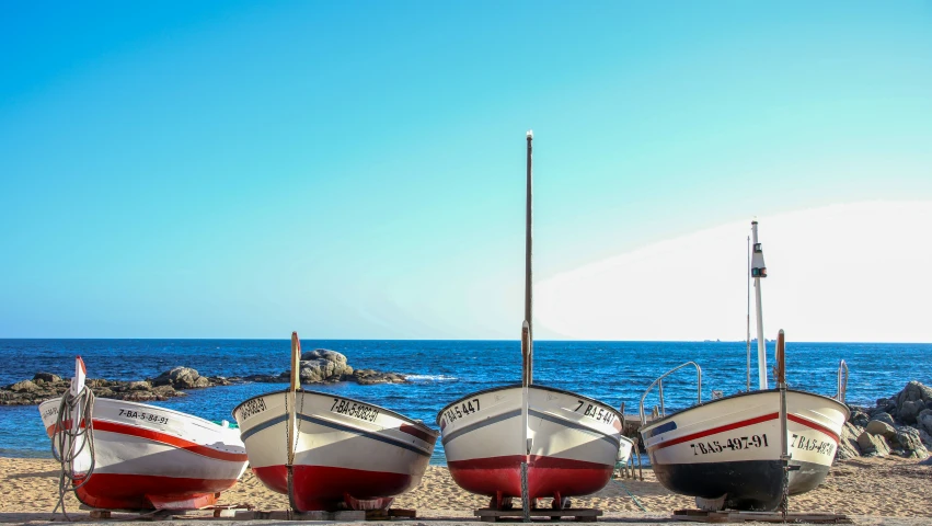 a group of four small boats sitting on top of a beach