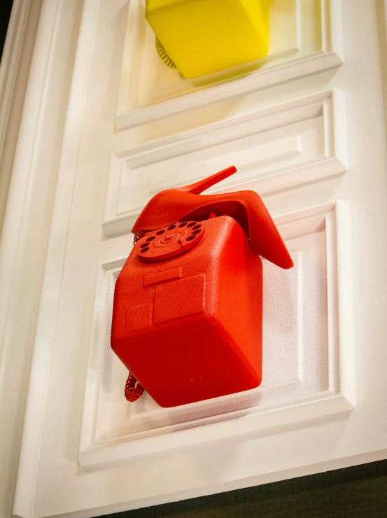 a red object hangs in the window by some yellow containers