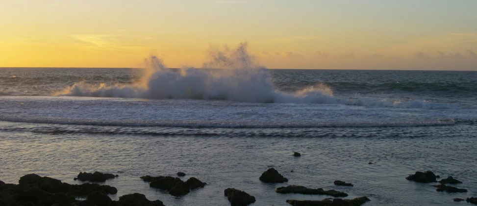 a crashing wave in the middle of a sandy beach