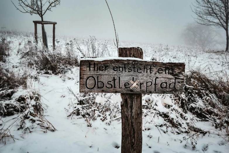 a wooden sign in a field with snow on it