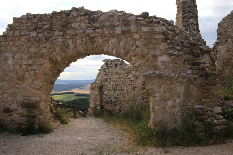 an archway between two ruined brick walls, leading to a walkway