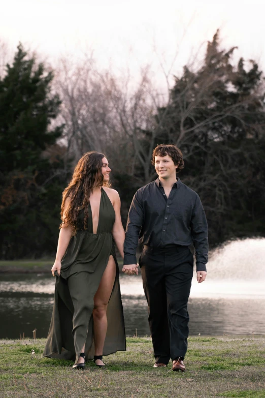 a couple walks holding hands by a pond