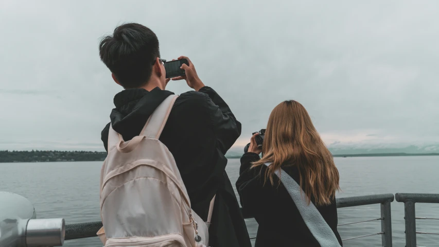 two people standing next to each other and taking pictures