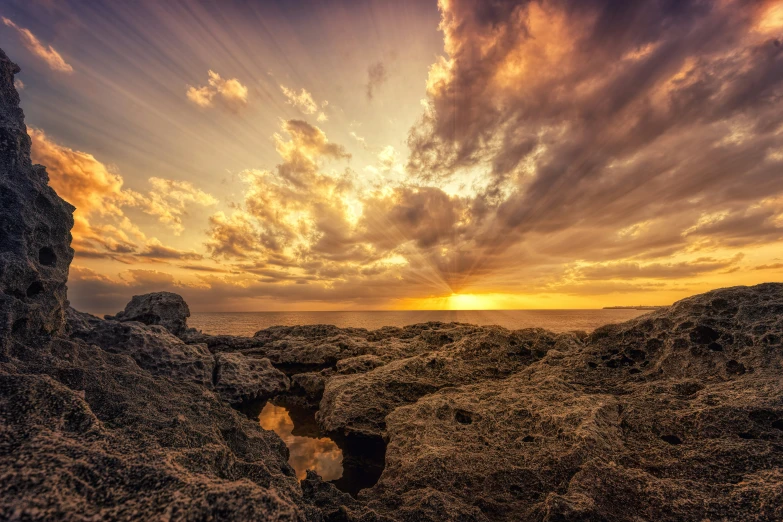 a rocky coast area with water flowing out from it at sunset