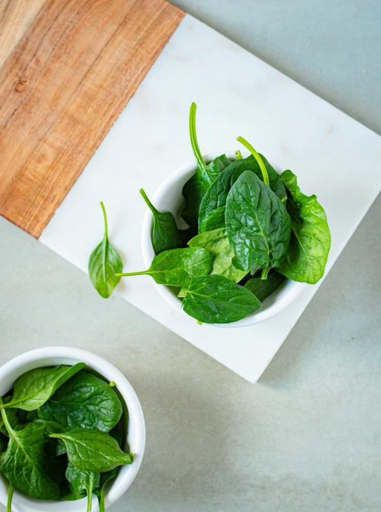 small white bowls filled with leafy greens on top of a table