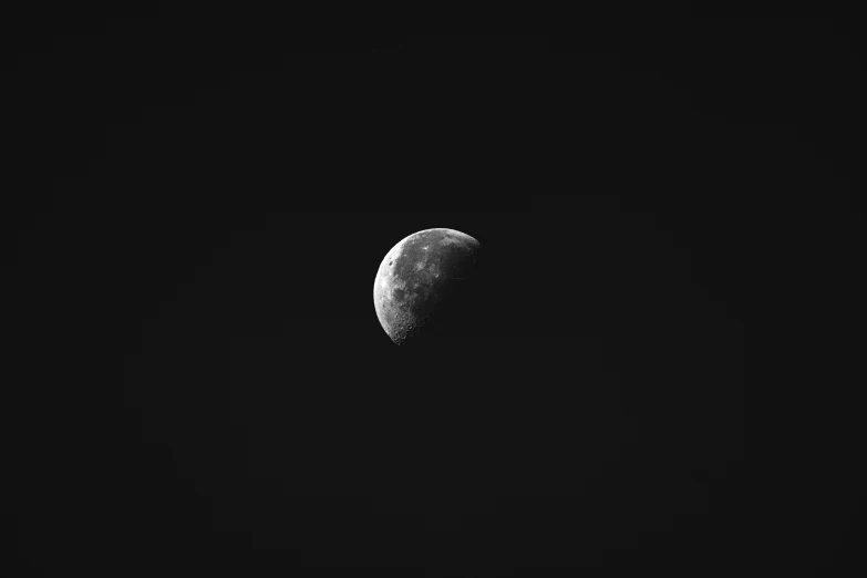 a half moon seen in black and white against a dark background