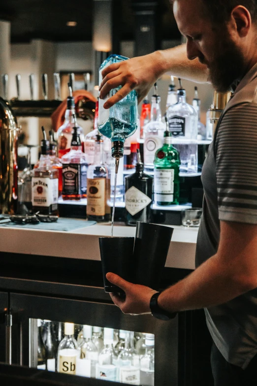 a man pouring drinks behind a bar in a building