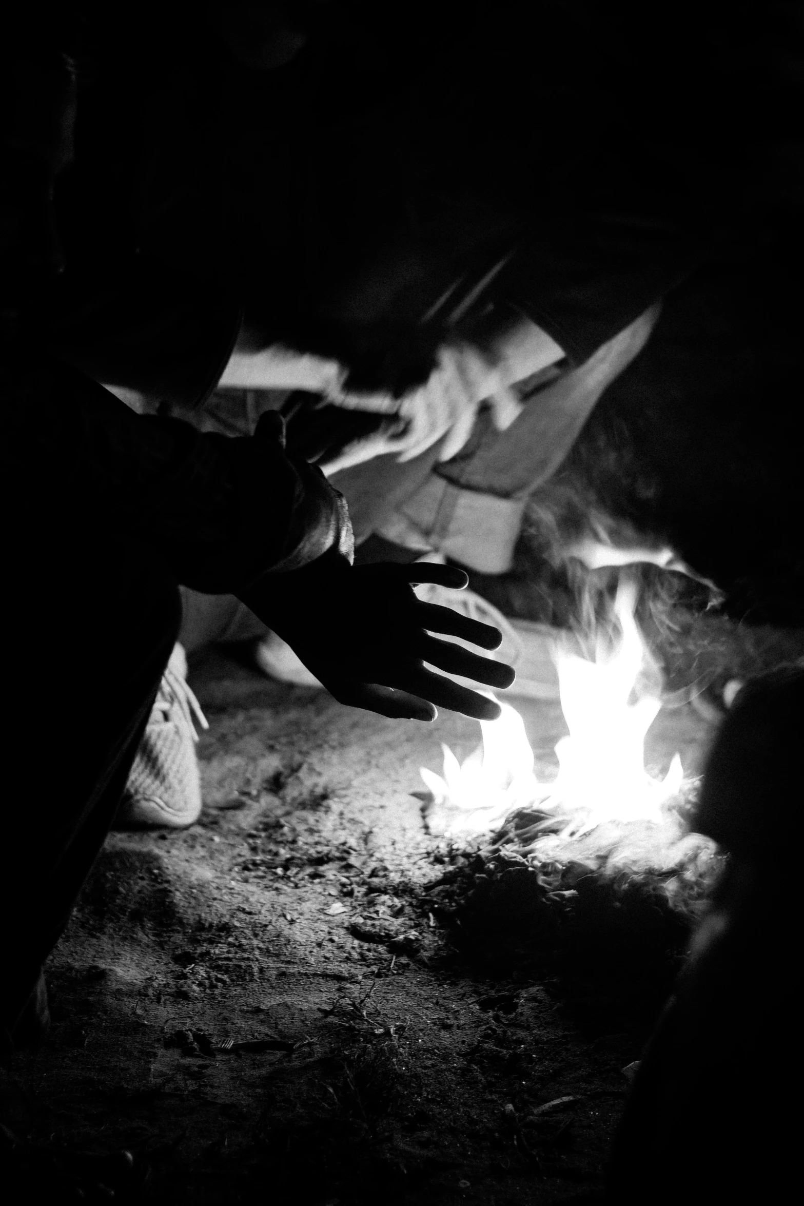 hands touching each other over fire in black and white