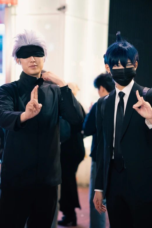 two men in black clothes one with white hair and a white blindfold