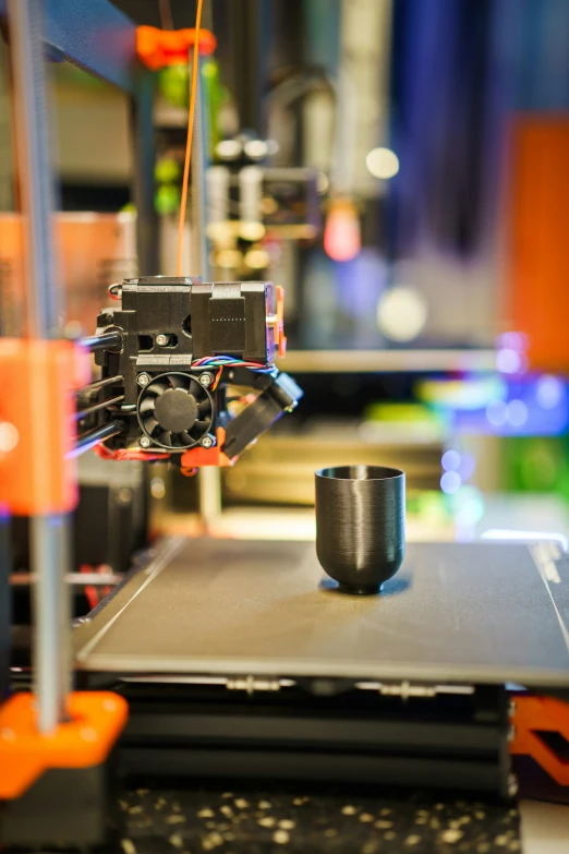 a 3d printer with coffee mug in front of it