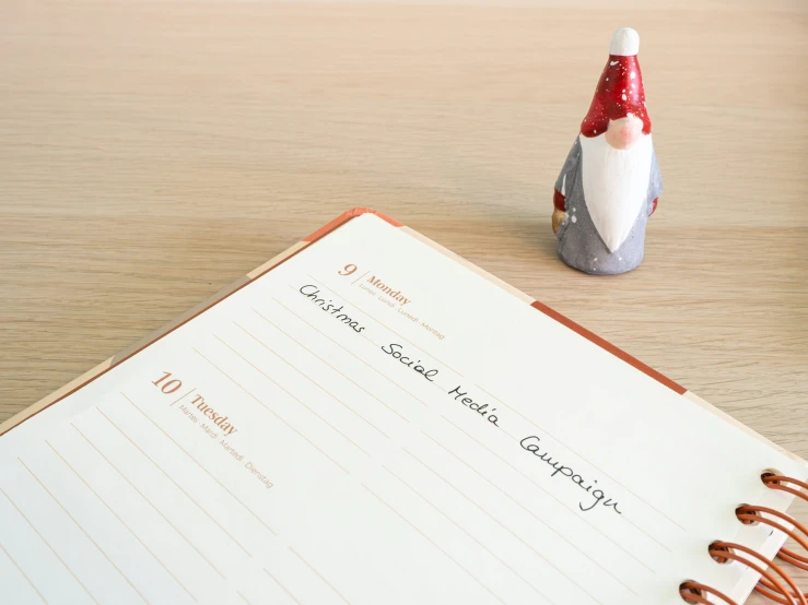 a santa's gnome figurine is on top of a lined notepad