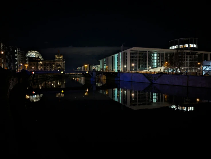 a large building on the other side of the water at night