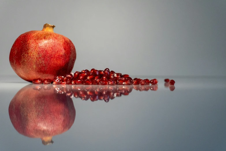 a pomegranate laying next to each other on the reflective surface