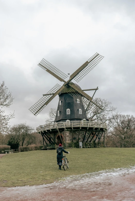 a person walking a bike past a windmill