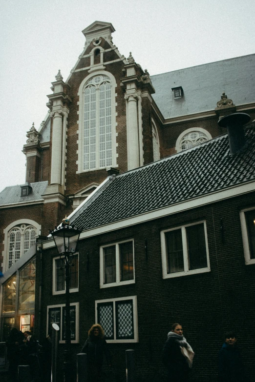 some people standing outside of a building with lots of windows