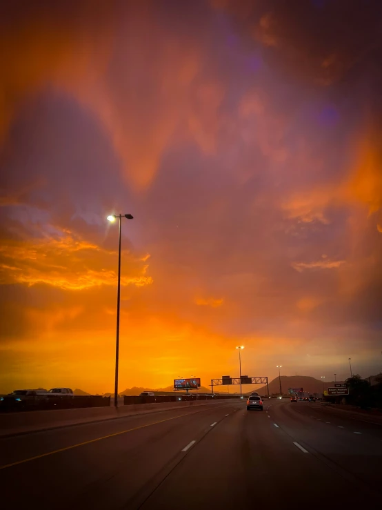 the sun is setting on the side of a road