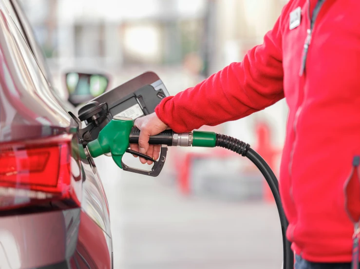 someone with red jacket filling up the car at a gas station