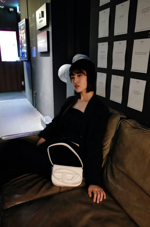 a woman is posing on the couch holding a handbag