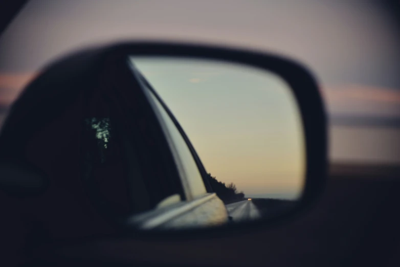 a view through a side mirror of a car of the beach